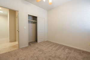 Unfurnished bedroom with light colored carpet, a closet, and a ceiling fan