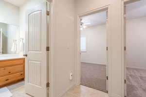 Bathroom with vanity, ceiling fan, light colored carpet, and light tile patterned floors