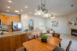Dining space with arched walkways, a fireplace, a ceiling fan, ornamental molding, and recessed lighting