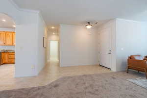 Living area featuring light carpet, crown molding, arched walkways, and recessed lighting