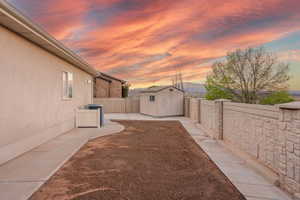 Yard at dusk with a storage unit and a fenced backyard