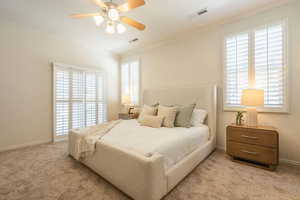 Bedroom featuring light carpet, ornamental molding, and ceiling fan