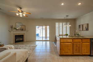 Kitchen with open floor plan, wood finish cabinets, ornamental molding, light stone counters, and light tile patterned floors