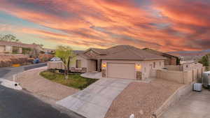 View of front facade featuring a garage, concrete driveway, stone siding, and stucco siding