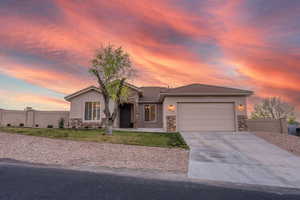 Ranch-style home featuring stone siding, an attached garage, concrete driveway, and stucco siding