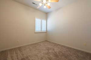 Carpeted empty room featuring ceiling fan and baseboards