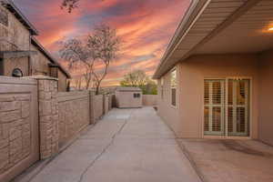 Patio terrace at dusk with a storage unit, a fenced backyard, and a patio area
