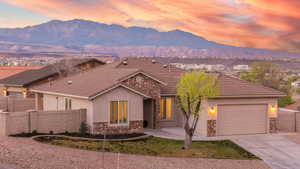 Ranch-style home featuring stone siding, an attached garage, concrete driveway, and stucco siding