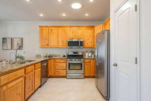 Kitchen featuring stainless steel appliances, light stone countertops, crown molding, recessed lighting, and a peninsula