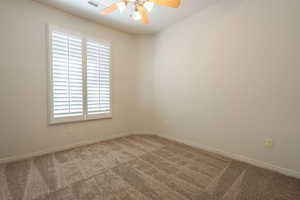 Empty room with a ceiling fan and carpet floors