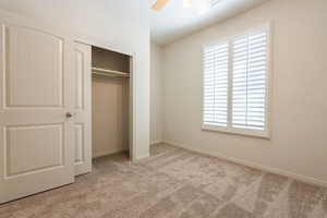 Unfurnished bedroom with light carpet, a closet, and a ceiling fan