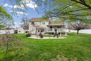 Rear view of property with a fenced backyard, a storage unit, covered porch, a patio area, and a fire pit