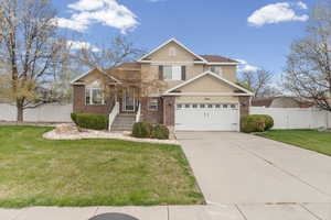 Traditional-style home featuring concrete driveway, brick siding, a garage, and stucco siding