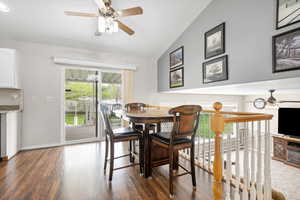 Dining area featuring ceiling fan, dark wood-style flooring, and lofted ceiling
