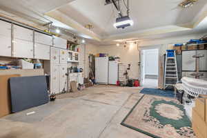 Garage featuring freestanding refrigerator, a garage door opener, and white refrigerator