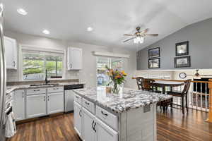 Kitchen with a ceiling fan, dark wood-style floors, white cabinetry, light stone countertops, and vaulted ceiling