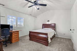 Bedroom featuring lofted ceiling, a ceiling fan, light carpet, and an office area