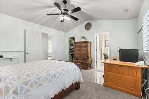 Bedroom featuring a walk in closet, a desk, ceiling fan, light colored carpet, and ensuite bathroom