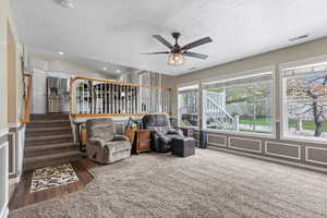Living room with a decorative wall, a ceiling fan, a wainscoted wall, a textured ceiling, and recessed lighting