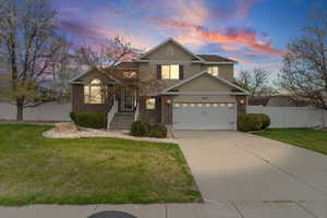 Traditional-style home featuring concrete driveway, brick siding, an attached garage, and stucco siding