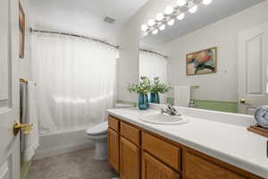 Bathroom with vanity, shower / bath combo with shower curtain, and a textured ceiling
