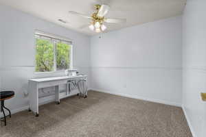 Home office with light colored carpet and a ceiling fan