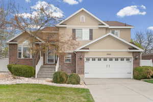 Traditional-style home featuring brick siding, stucco siding, concrete driveway, and a front yard