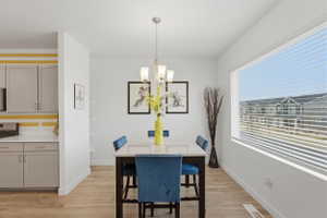 Dining room with light wood-style floors and suspended lighting