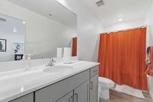 Bathroom with vanity, light wood-style flooring, shower / bath combination with curtain, and recessed lighting