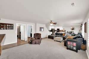 Living area with ceiling fan and light carpet