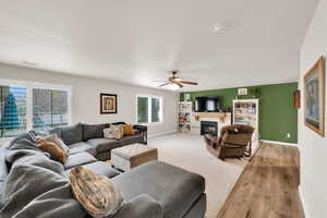 Living room featuring wood finished floors, a glass covered fireplace, and ceiling fan