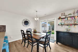 Dining room with light wood-style floors and suspended lighting