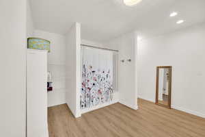 Full bath with light wood-type flooring, recessed lighting, and shower / bath combo
