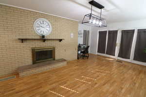 Unfurnished living room featuring a desk, wood finished floors, and a brick fireplace