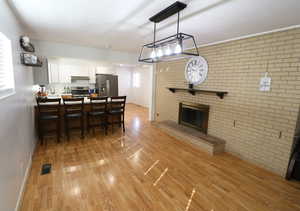 Kitchen featuring brick wall, a peninsula, light wood finished floors, a kitchen breakfast bar, and stainless steel appliances