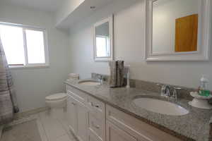 Full bathroom with double vanity, light tile patterned floors, and a shower with shower curtain