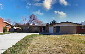 Ranch-style house featuring brick siding, a garage, driveway, and a front yard