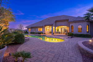 Pool at dusk with a patio area and a pool with connected hot tub