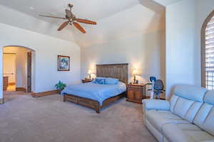 Bedroom featuring arched walkways, carpet, ceiling fan, vaulted ceiling, and multiple windows
