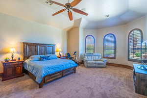 Carpeted bedroom featuring a ceiling fan and vaulted ceiling