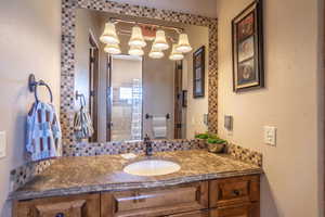 Bathroom featuring a textured wall, vanity, and tasteful backsplash