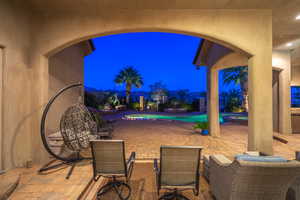 Patio at twilight with a patio area, a pool with connected hot tub, and a fenced backyard