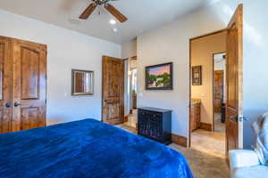 Bedroom with light colored carpet, ceiling fan, and light tile patterned floors