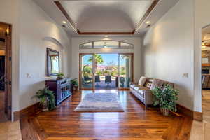Living area with a raised ceiling, recessed lighting, hardwood / wood-style flooring, ceiling fan, and arched walkways