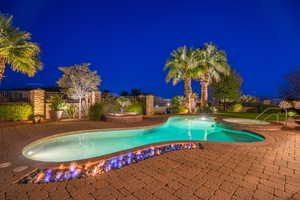 Pool at night featuring an in-ground hot tub, a patio, and a fenced backyard