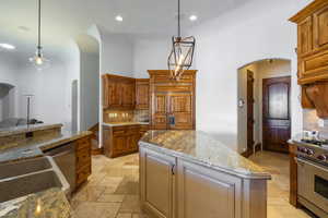 Kitchen featuring arched walkways, backsplash, stainless steel appliances, and stone tile flooring