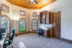 Carpeted office with a high wooden ceiling, a ceiling fan, and built in study area