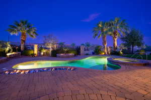 Pool at dusk with a fenced backyard, a pool with connected hot tub, and a patio area