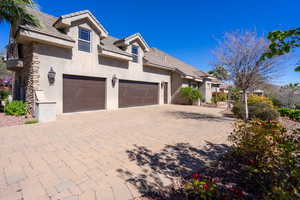 View of front facade with decorative driveway, a tile roof, stucco siding, a gate, and an attached garage