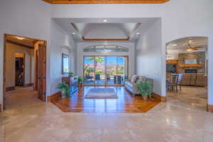 Foyer with a ceiling fan, a fireplace, recessed lighting, arched walkways, and a raised ceiling